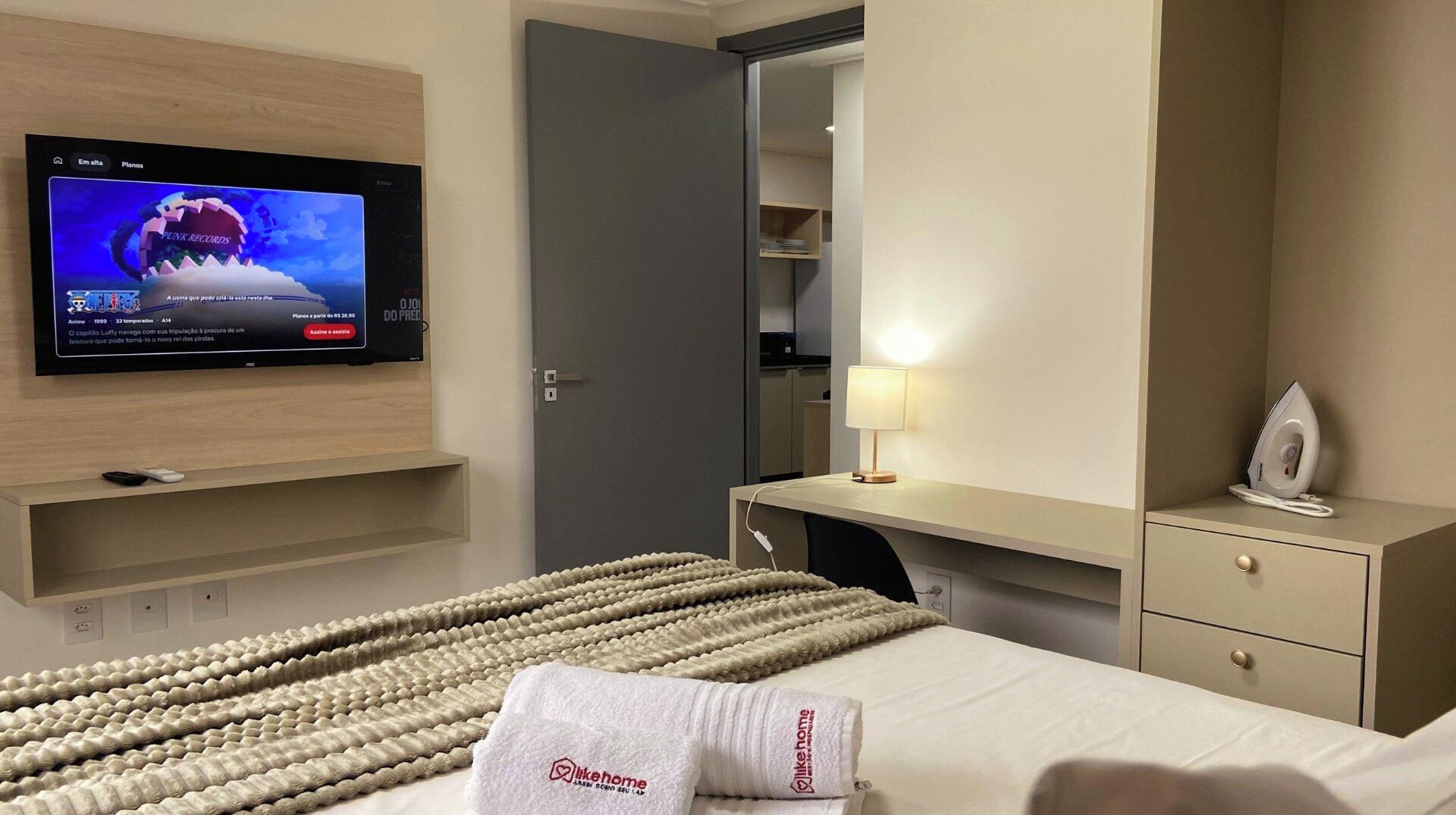A hotel room with a bed, a desk, a television, and a mirror.