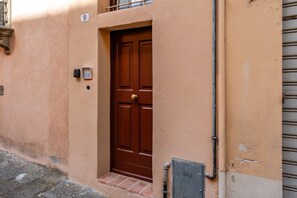 A brown door with a number '9' above it, a small window with a metal grill, and a utility box on the ground. - Nami House – Modern Comfort in the Heart of Lucca (Lucca)