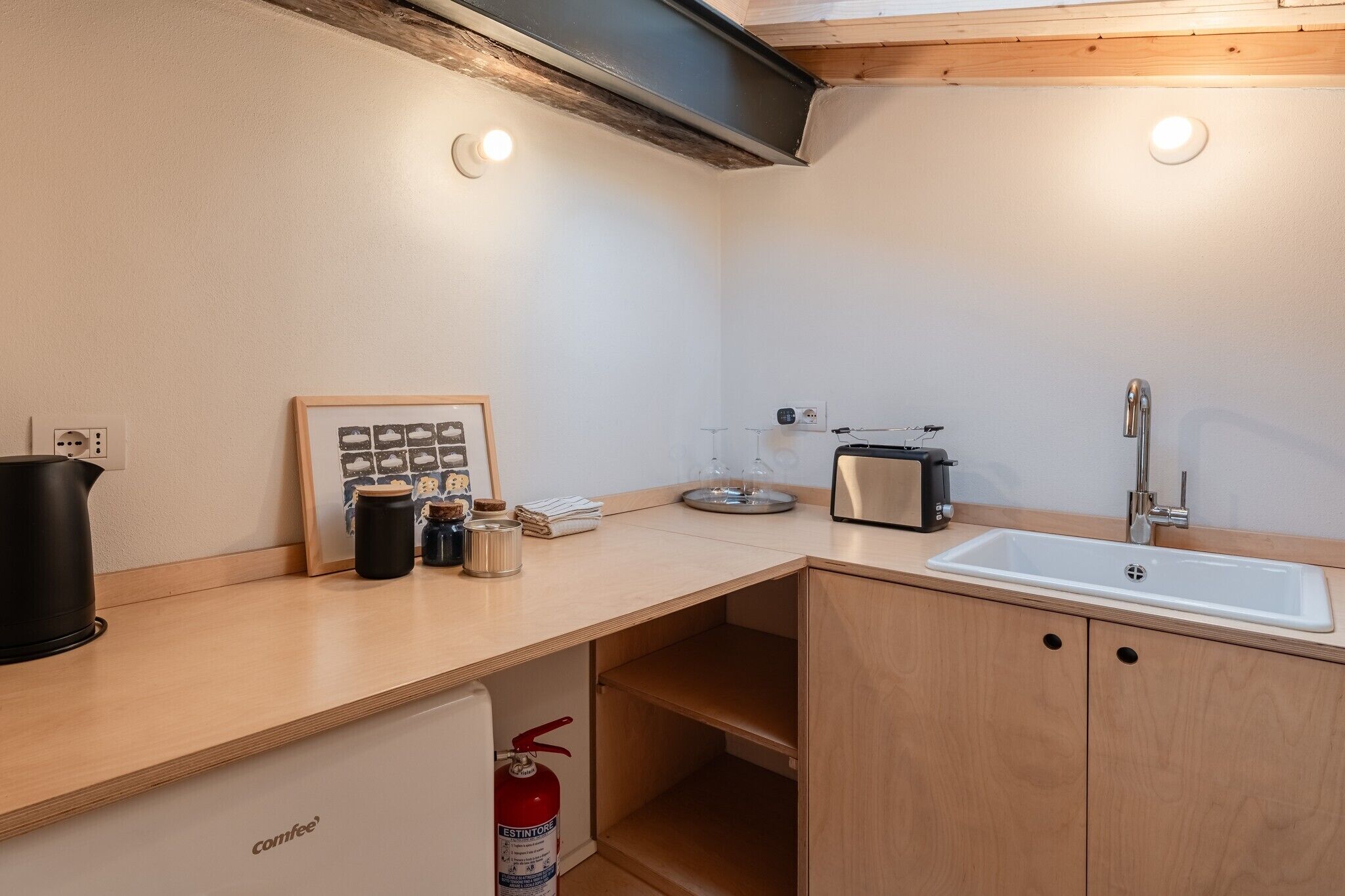 Una cocina compacta con un lavamanos, un tostador y una foto enmarcada sobre la encimera.