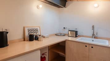 Una cocina compacta con un lavamanos, un tostador y una foto enmarcada sobre la encimera.