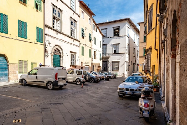 Une rue étroite bordée de voitures garées et de bâtiments à l’architecture traditionnelle.