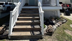 Een tweelaags huis met een veranda, houten trappen en een brievenbus.