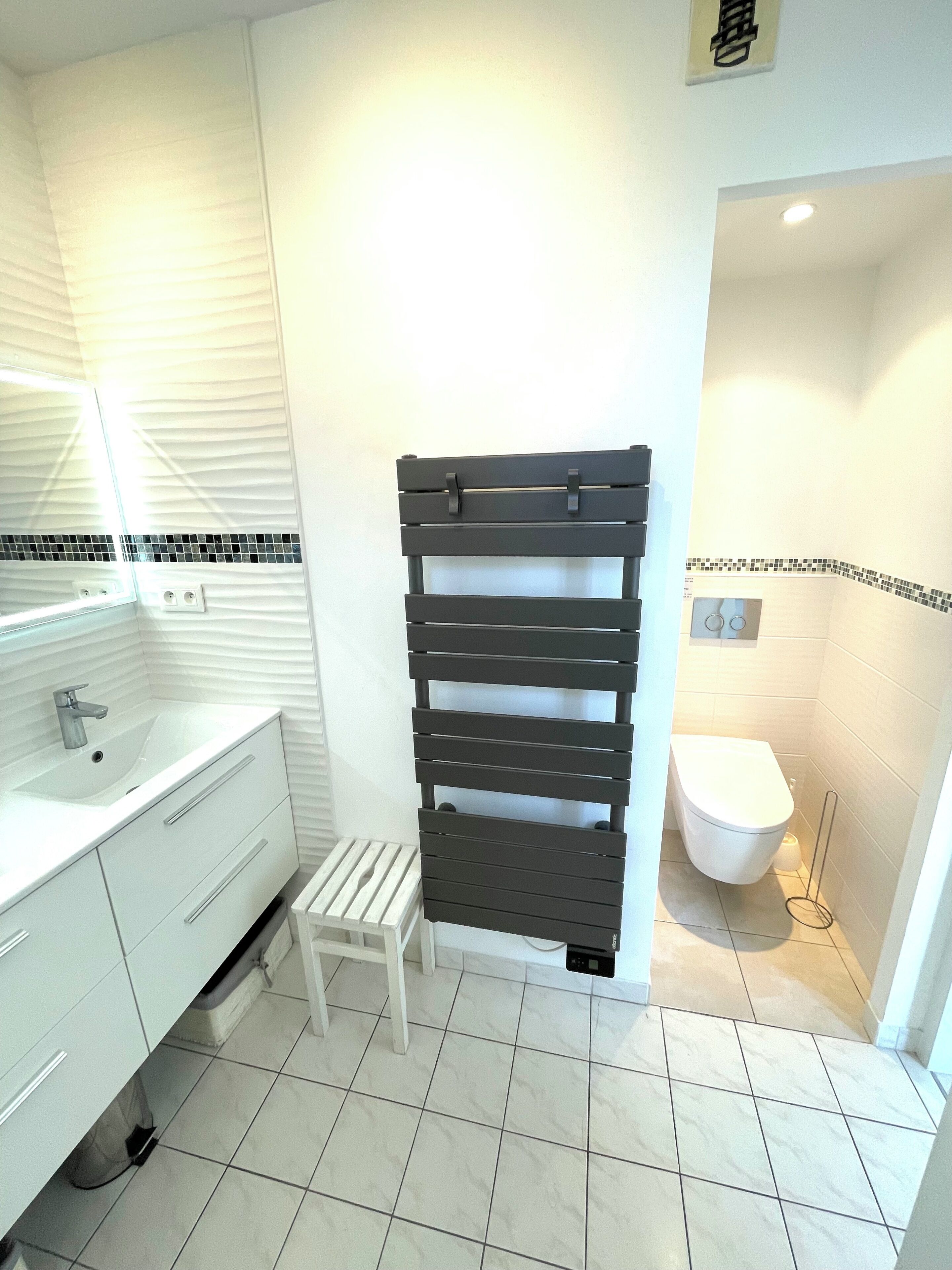 Une salle de bain avec un lavabo blanc, des toilettes et un espace douche.