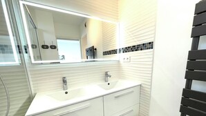 A bathroom with two sinks, a mirror, and a towel rack. - Apartment with a large terrace (Cavalaire-sur-Mer)