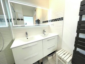 A bathroom with two sinks, a mirror, and a towel rack. - Apartment with a large terrace (Cavalaire-sur-Mer)