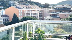 A residential area with multi-story buildings, balconies, and a hillside in the background. - Apartment with a large terrace (Cavalaire-sur-Mer)