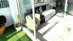A modern living room with a glass door leading to a balcony, a sofa, a coffee table, and a dining area. - Apartment with a large terrace (Cavalaire-sur-Mer)
