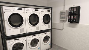 A laundry facility with four front-loading washing machines and a control panel. - Beddy Hostels (Madrid)