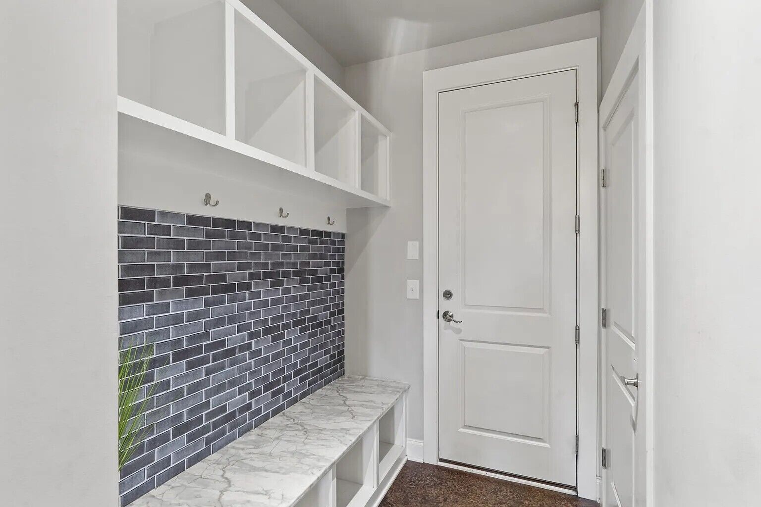 A hallway with a white door, a white bench, and a tiled wall.