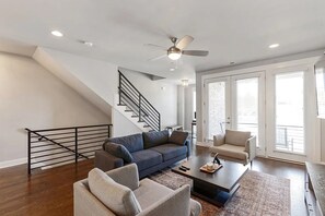Ein modernes Wohnzimmer mit Treppe, Deckenventilator und großem Fenster.