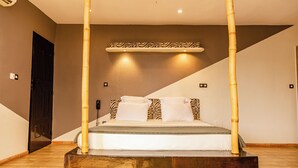 Um quarto com uma cama, uma porta e uma prateleira fixada na parede.