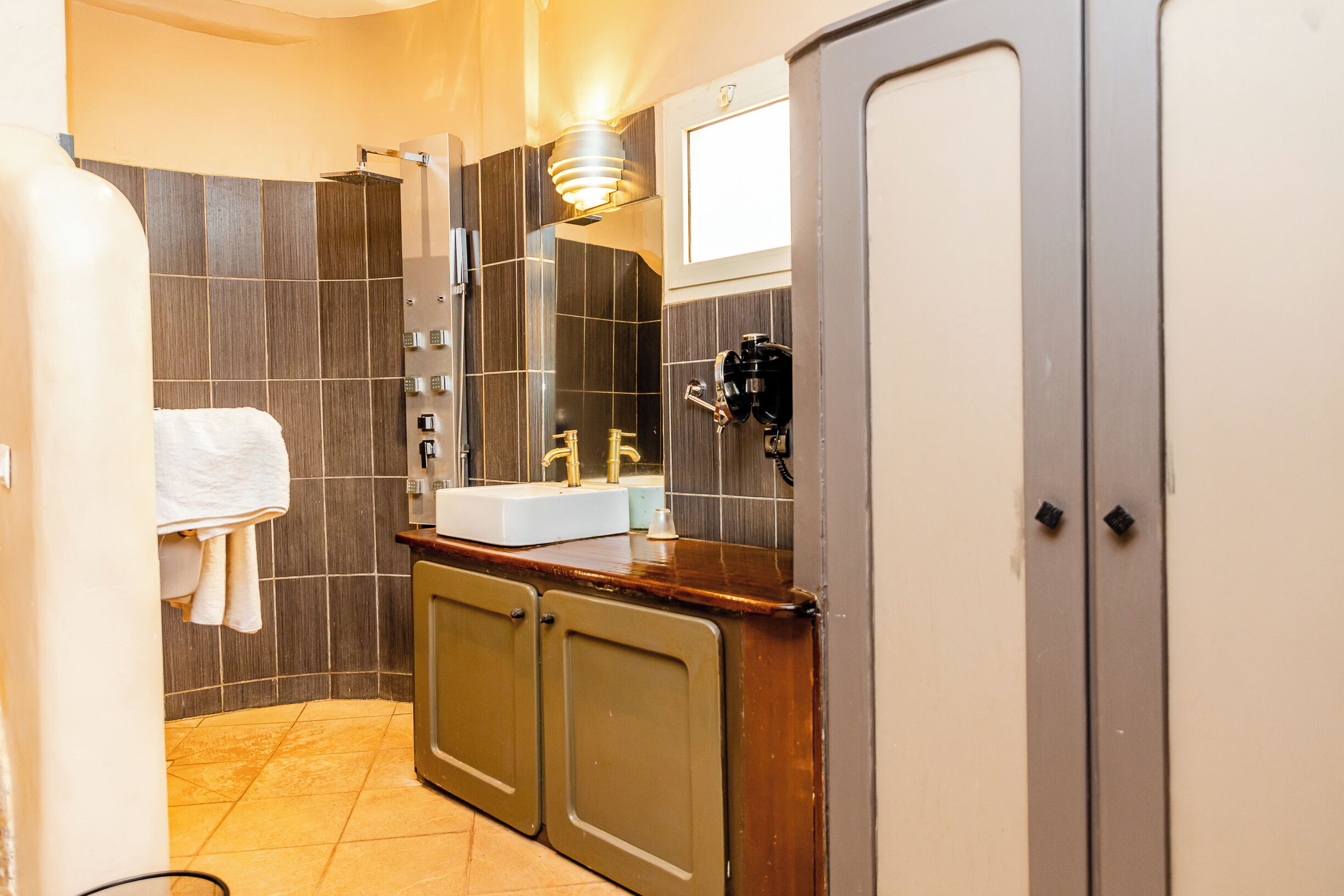 Un bagno con lavandino, specchio, porta asciugamani e doccia.