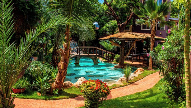 Um jardim exuberante com piscina, uma ponte e um gazebo.