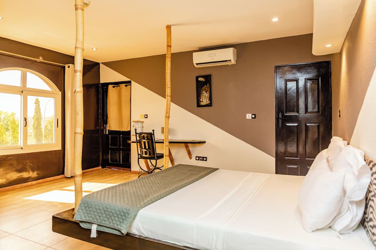 A room with a bed, a window, a door, and an air conditioning unit.