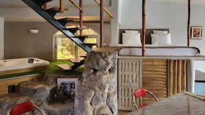 Um interior moderno com lareira de pedra, hidromassagem e escada com guarda-corpos de madeira.