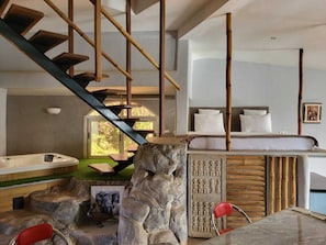 A modern interior with a stone fireplace, a hot tub, and a staircase with wooden railings.