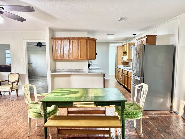 Une cuisine avec des meubles de rangement en bois, un réfrigérateur en acier inoxydable et une table à manger avec des chaises.