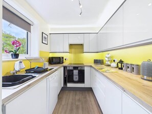 A modern kitchen with white cabinets, a microwave, a toaster, and a coffee machine. - Amazing Place Aviemore (Aviemore)