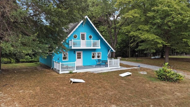 Une maison à deux étages avec un porche blanc et une petite terrasse.