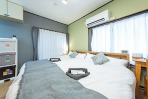A hotel room with a bed, a desk, an air conditioner, a wardrobe, and a window with curtains. - Convenient to stay in Tokyo, a house in a quiet residential area, good access to central Tokyo, 40 min. to Shinjuku and Akihabara, 2BR. (板橋区)