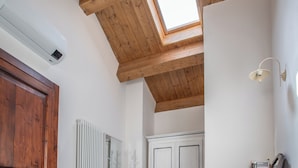 Une pièce dotée d’une lucarne, de poutres en bois au plafond, d’un radiateur blanc et d’une armoire blanche.