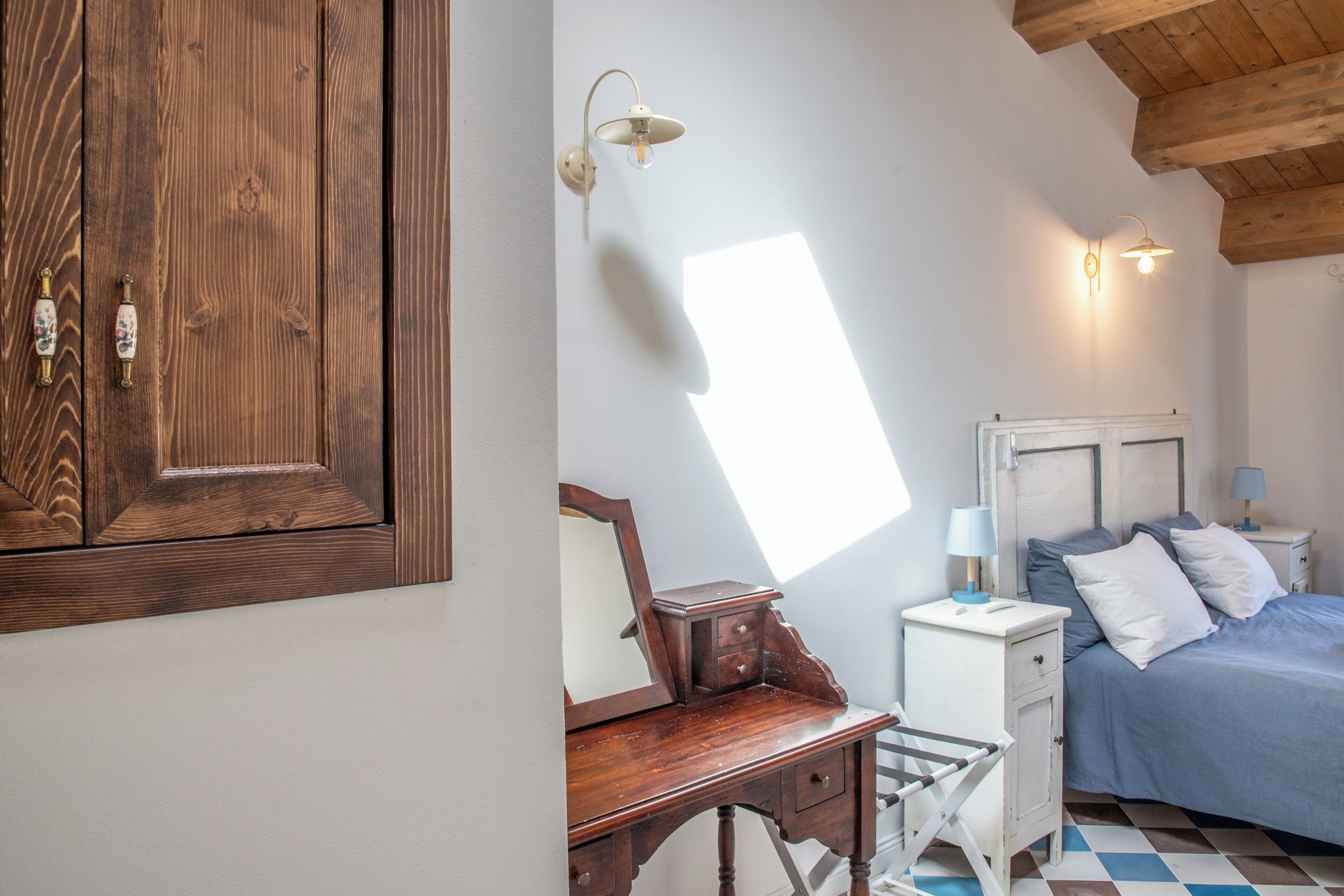 A bedroom with a bed, bedside tables, a dresser, a mirror, and a wardrobe.
