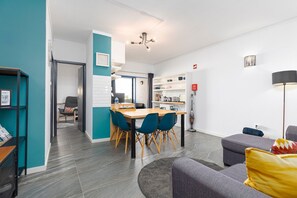 Una sala de estar moderna con un sofá, un comedor con sillas y una mesa, una cocina con estanterías y un pasillo que lleva a otra habitación.