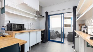Een kleine keuken met een magnetron, spoelbak en een eethoek.