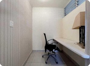 A small, clean room with a single black office chair, a white desk, and a white wall. - Comfortable studio in the city center (Santo Domingo)