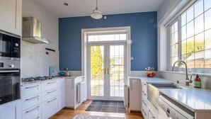 Eine moderne Küche mit weißen Schränken, Edelstahlgeräten und einem großen Fenster.
