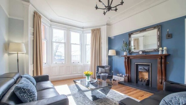 Ein Wohnzimmer mit Kamin, einer Couch, einem Couchtisch und einem großen Fenster.