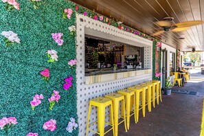 Un restaurante con una pared verde decorada con flores, una barra y taburetes amarillos.