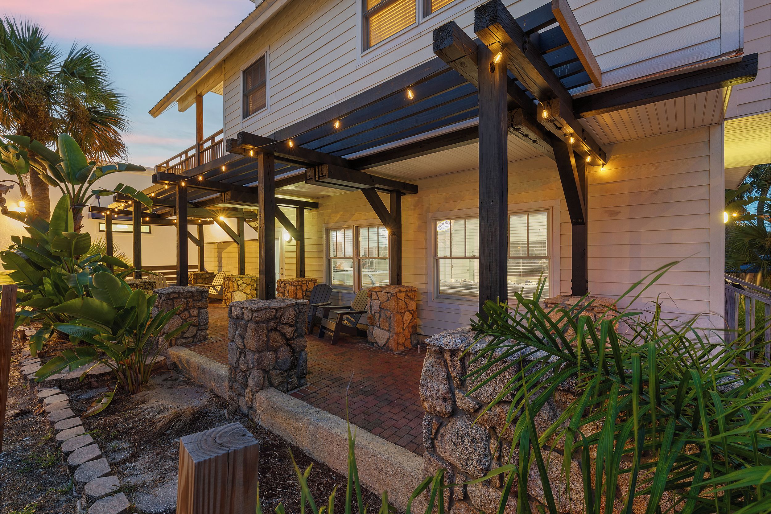 A house with a covered patio area, stone seating, and a view of the street.