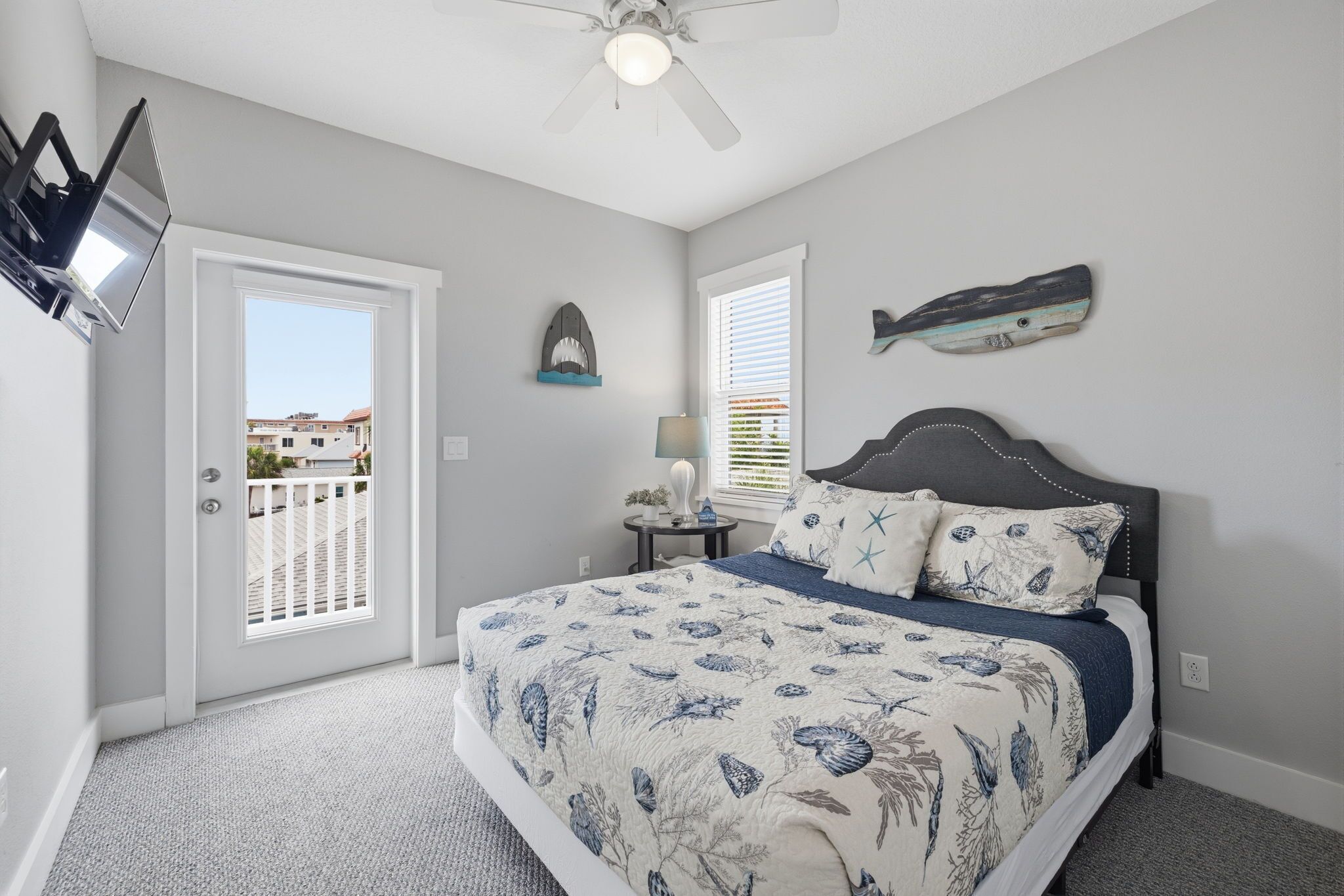 A bedroom with a bed, a ceiling fan, a door, and a window.