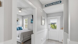 Een slaapkamer met een bed, een plafondventilator en een deur die leidt naar een balkon.