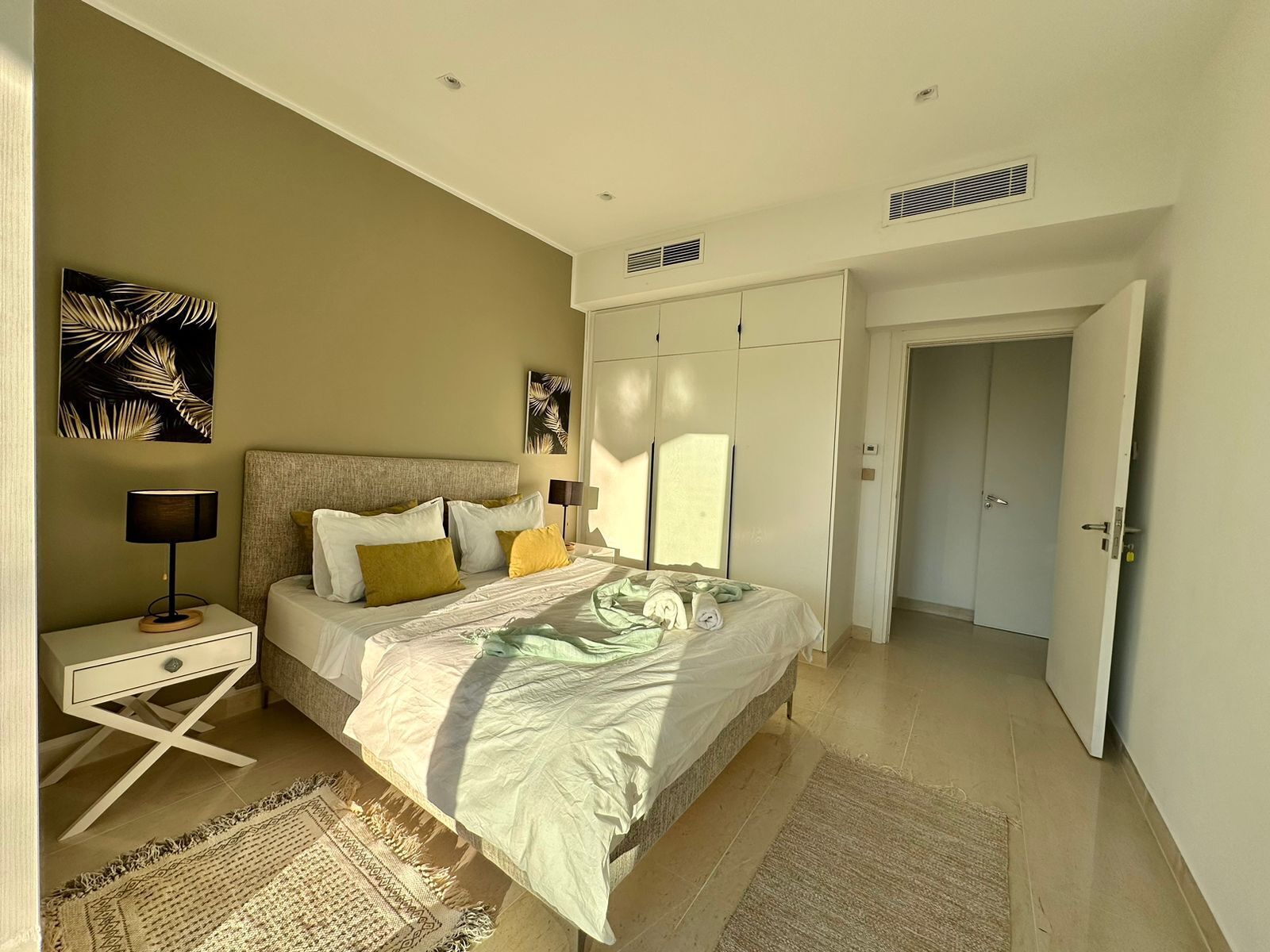 A bedroom with a bed, bedside tables, a nightstand, a door, and a hallway.