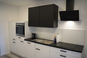Cuina moderna amb forn integrat, rentamicroones d'acer inoxidable i armaris negres.