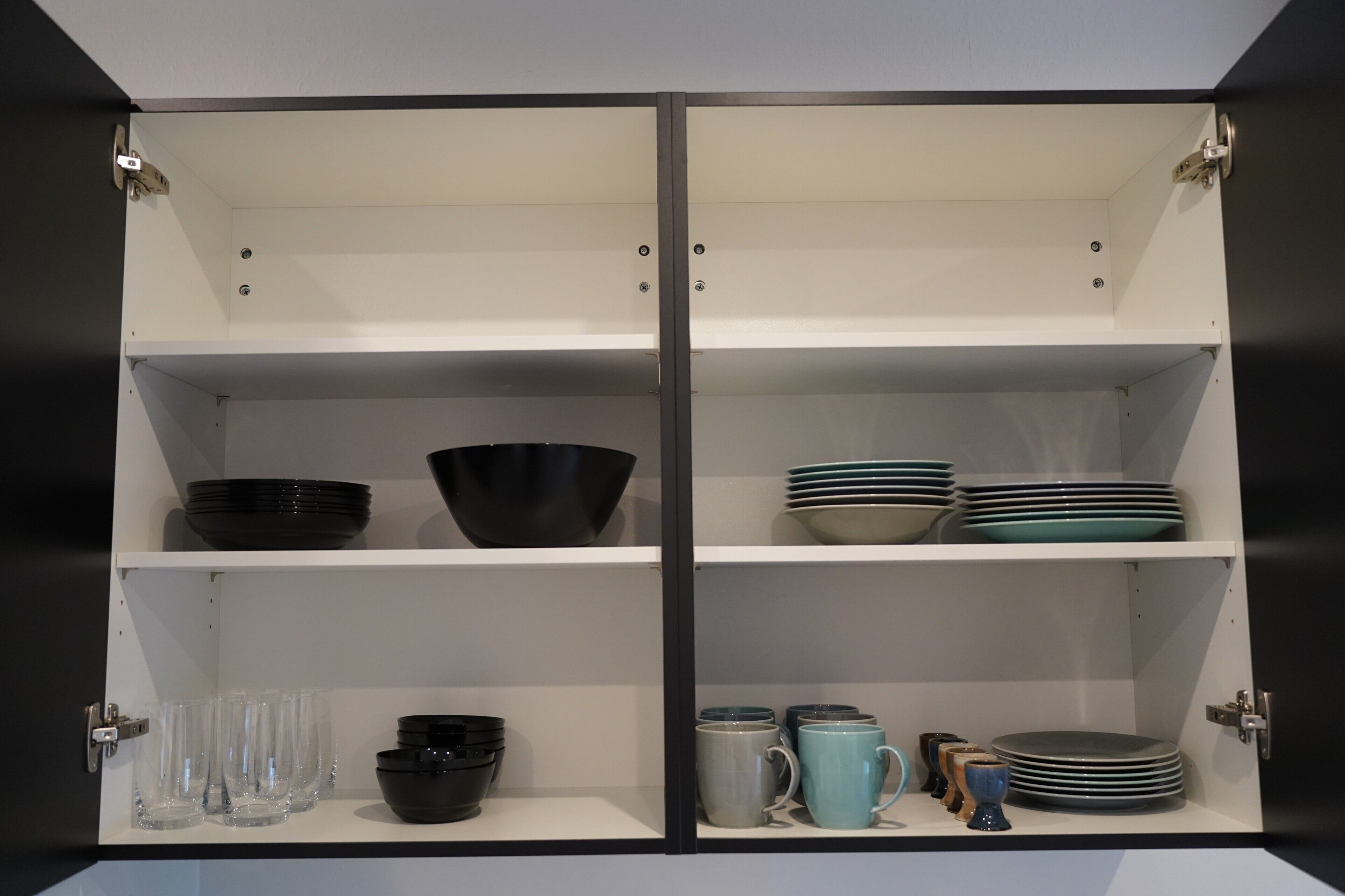 Ein Schrank mit Regalen, der verschiedene Küchenutensilien beherbergt.