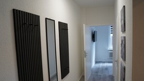 Un couloir avec une porte, un téléviseur fixé au mur et des œuvres d’art encadrées.