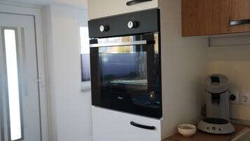 Een keuken met een zwarte oven, een koffiezetapparaat en een kom op het aanrecht.