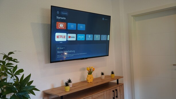 Ein Flachbildfernseher an der Wand, darunter eine Holzkonsole.