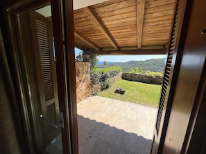 An open door leading to a patio with stone walls, a view of the countryside, and a stone pathway. - VILLA COSTA STELLA|Sea View, Private Pool&Relaxing Garden near San Teodoro (Comune di San Teodoro)