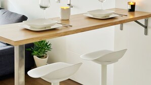 A modern kitchen with a wooden countertop, white bar stools, and a small potted plant.