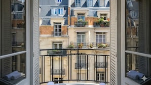 A balcony with a view of neighboring buildings, featuring balconies with flower boxes and a black metal railing. - celine 18 (Paris)