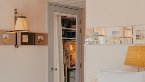 Un dormitorio con cama, lámpara de noche, armario y espejo con una obra de arte.