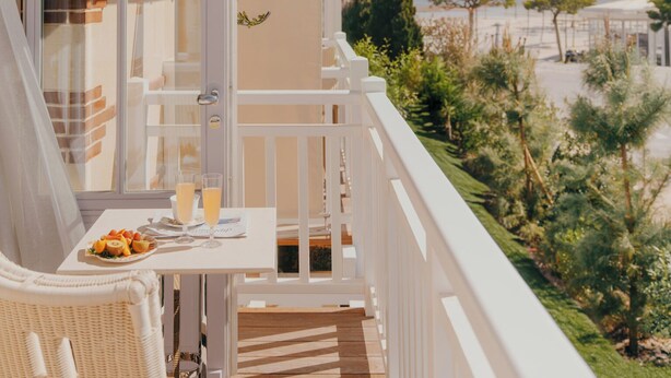 Un balcón con mesa dispuesta para dos personas, con vistas a un paisaje costero.