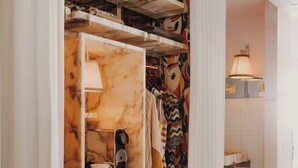 Vestidor con tocador de mármol, ropa colgada y cortina estampada.