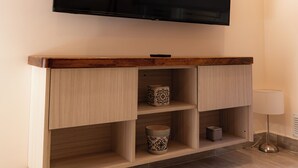 A flat-screen TV mounted on a wall above a wooden console with shelves. - Enjoy with your family the best view of the waterfall I Ayres del Bosque Accommodations (San Martín de los Andes)
