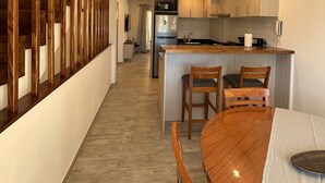 A modern kitchen with wooden cabinets, a central island, and a dining area with a table and chairs. - Enjoy with your family the best view of the waterfall I Ayres del Bosque Accommodations (San Martín de los Andes)