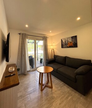 Un soggiorno con un divano, un tavolo in legno, una TV e un quadro appeso al muro.